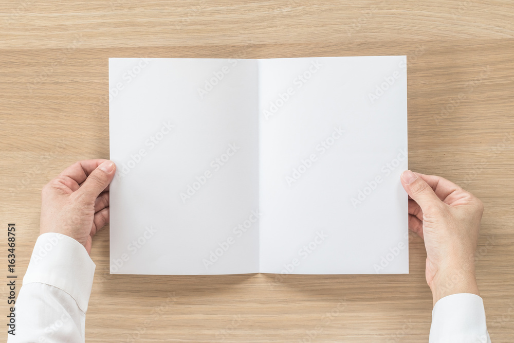 Mock up flyer pamphlet brochure design A5 size paper in business man's hand for template illustration mockup, flat lay on wood table from top view Mock up flyer pamphlet brochure design A5 size paper in business man's hand for template illustration mockup, flat lay on wood table from top view