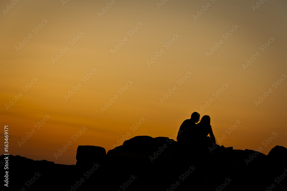Silhouettes of a couple sitting to each other