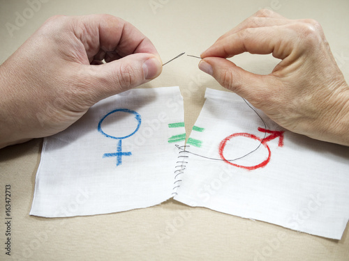 The hands of a man and a woman sewing the symbol of gender equality
