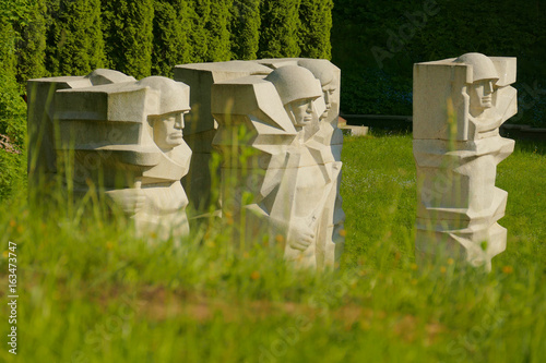 Monument depicting the silhouettes of Soviet soldiers at the Vilnius cemetery. Behind green grass there are blocks of stone from which carved soldiers in helmets. photo