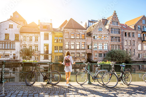 Sunrise view on the water channel with beautiful old buildings with woman standing near the bicycles in Gent city photo