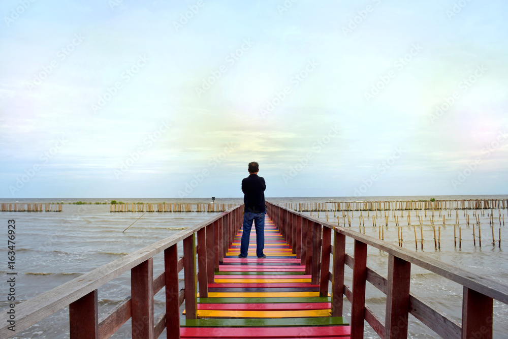 Men stand alone sea view on a wooden bridge