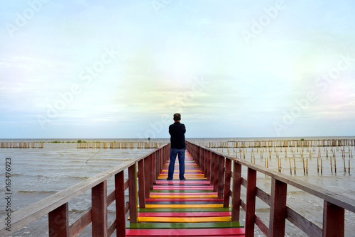 Men stand alone sea view on a wooden bridge