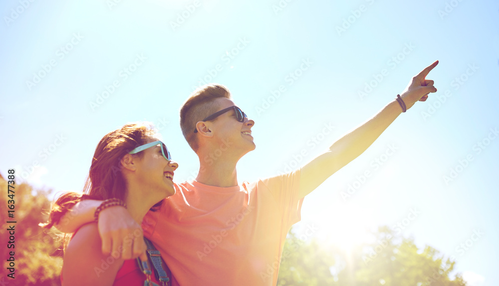 happy couple pointing finger at summer park happy couple pointing finger at summer park
