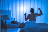 The man doing exercise near a woman on the bed. night time