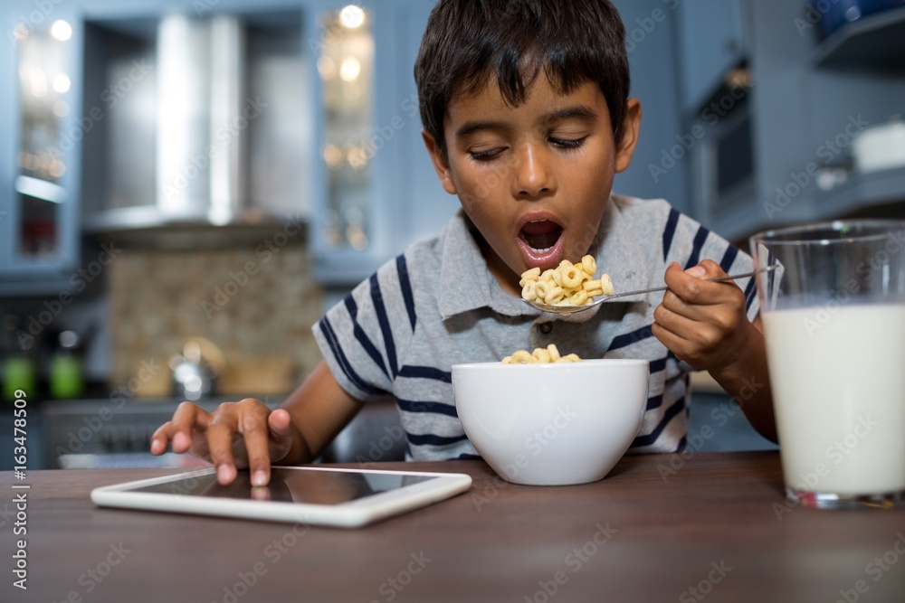 Close up of boy using tablet computer while having breakfast Close up of boy using tablet computer while having breakfast