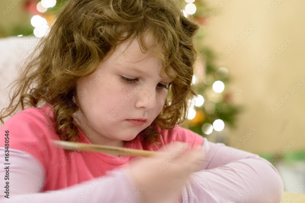 Cute little child girl writes the letter to Santa Claus near Christmas tree indoors. Cute little child girl writes the letter to Santa Claus near Christmas tree indoors.