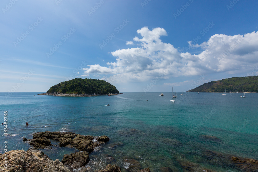  Jungle island surrounded by sailboats, clear water and blue skies.