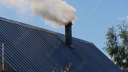 From the pipe goes gray smoke against the blue sky