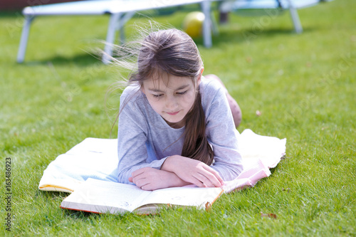 A girl reading book on a green meadow