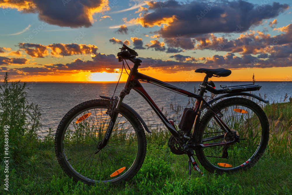 Fototapeta premium Bike by the river in the setting sun. Siberia, Russia