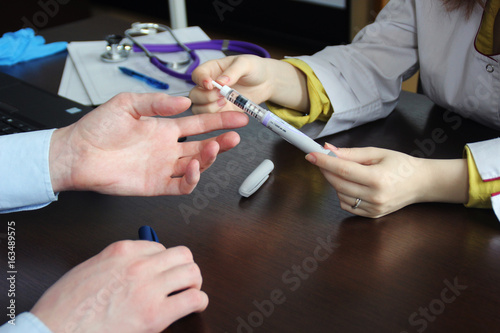 Close up of female doctor telling her patient about diabetes and showing insulin pen.Health care concept