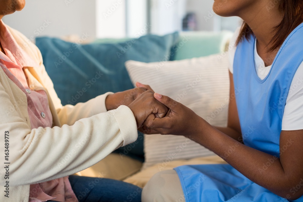 Obraz premium Female doctor comforting senior woman in living room
