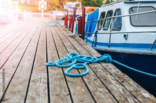 A blue yacht moored with a line tied around a fixing on the quayside/ Mooring at a pier