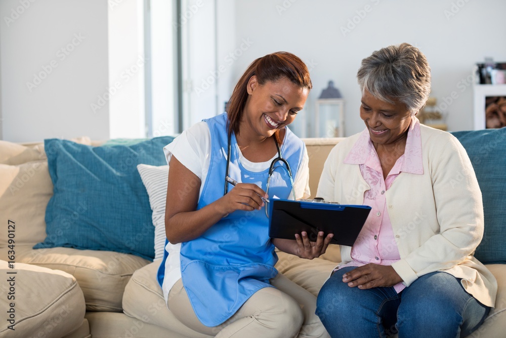 Doctor explaining medication on clipboard to senior Doctor explaining medication on clipboard to senior