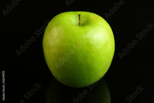 A fresh Granny Smith apple on a black background.