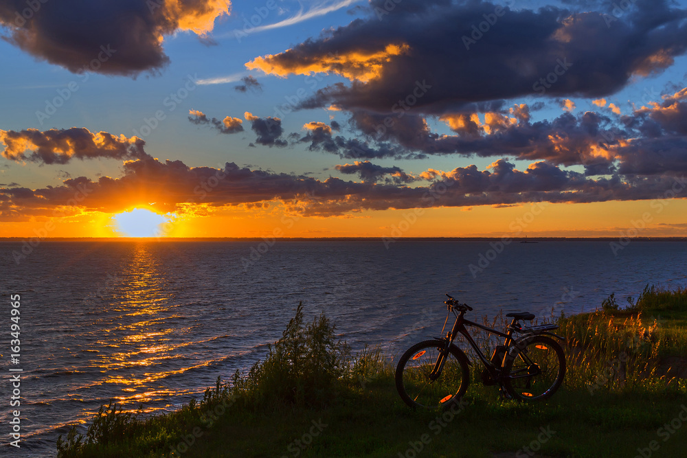 Fototapeta premium Bike by the river in the setting sun. Siberia, Russia