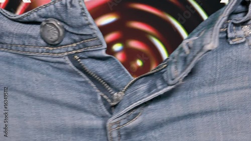 The hands of a woman opening the zipper of a pair of jeans, revealing the text XXX over spinning circles, dotty grindhouse low-budget b-movie style.
 photo