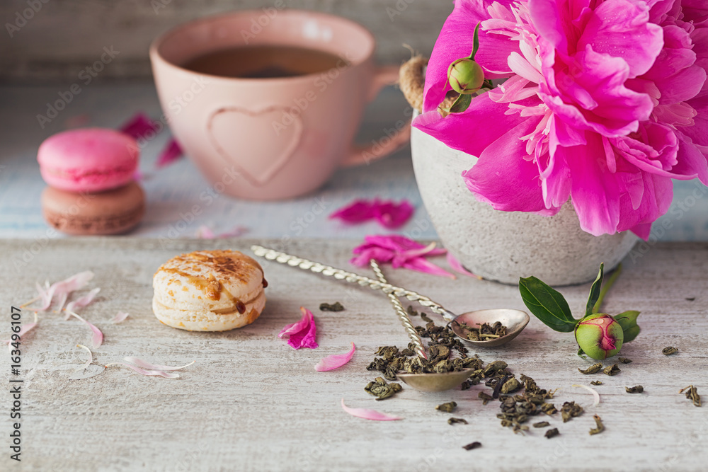 Still life with pink peony flowers and a cup of herbal or green tea Still life with pink peony flowers and a cup of herbal or green tea