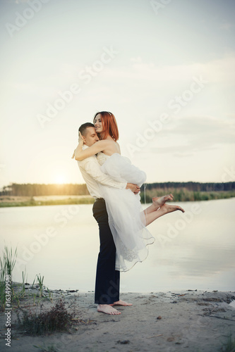 Elegant gentle stylish groom and bride near river or lake. Wedding couple in love photo