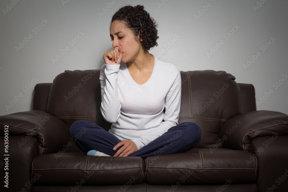 Young female has a cough and is sitting on the couch. Young female has a cough and is sitting on the couch.