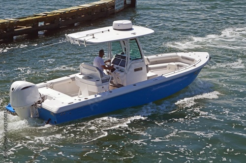 A small open sport fishing boat powered by a single outboard engine cruising the florida intra-coastal waterway near Miami Beach.