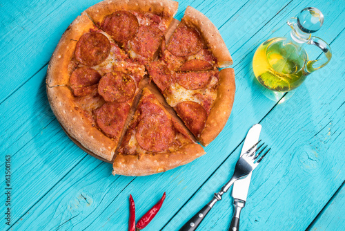 Pizza with khit and fork on blue wooden table. photo