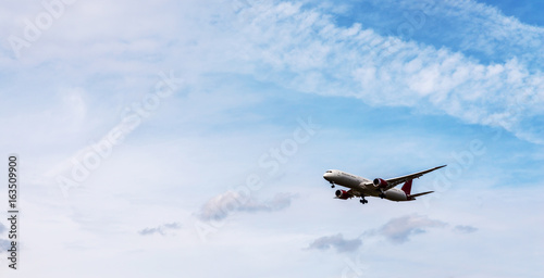 Passenger plane flying in the blue sky with clouds, cruise aircraft, transport industry