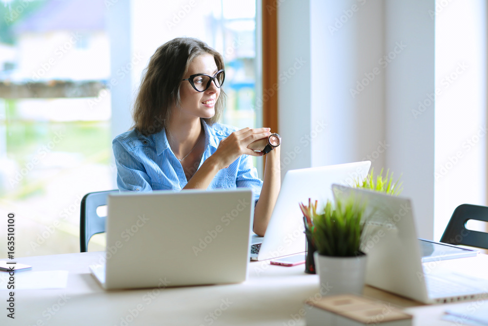 Young woman sitting at office table with laptop Young woman sitting at office table with laptop