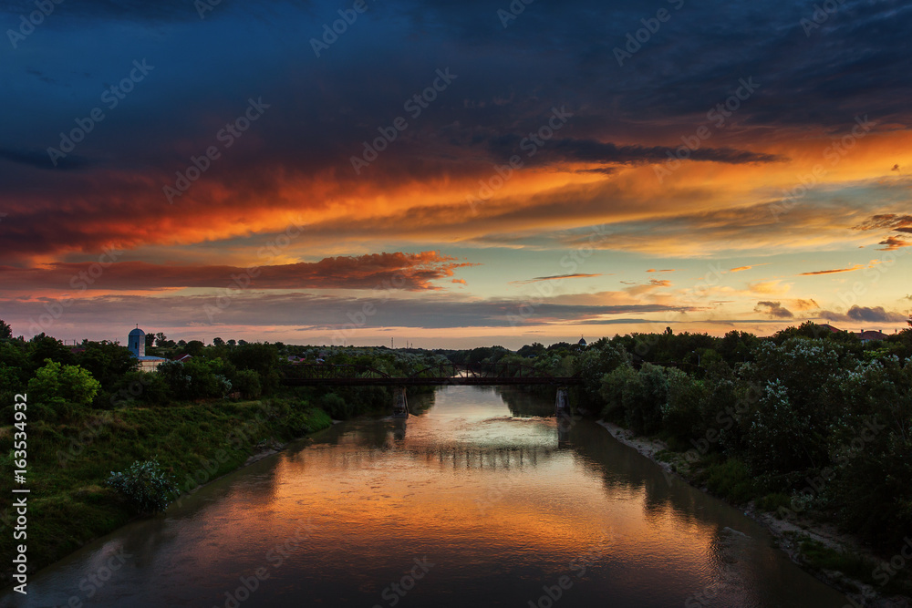 Sunset landscape over a river with beautiful colourful clouds in background