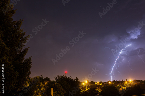 Thunder storm over houses in country side in the middle of the night with beautiful lightning in background