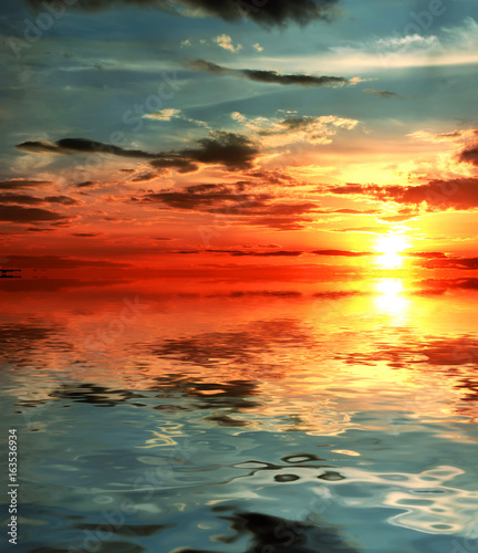 Beautiful sunset over sea with reflection in water, majestic clouds in the sky