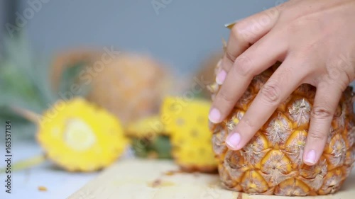 Close up shot hands of women using kitchen knife to cutting and peeling ripe pineapple shallow depth of field with ambient sound photo