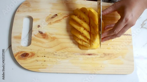 Close up shot hands of women using kitchen knife to cutting and peeling ripe pineapple shallow depth of field with ambient sound photo