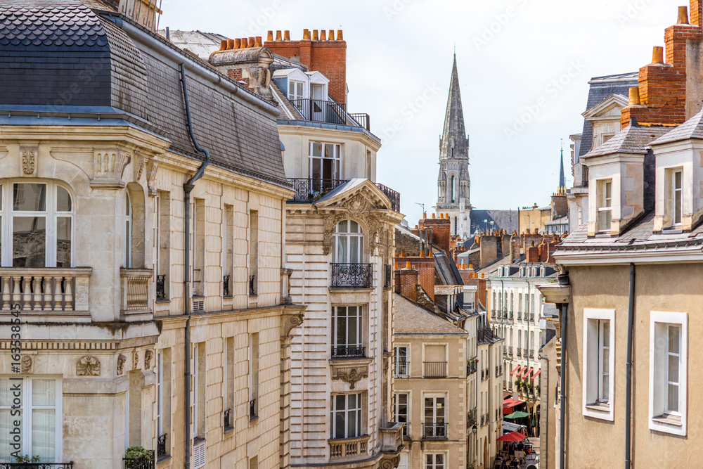 Fototapeta premium Street view on the beautiful residential buildings andchurch tower in Nantes city during the sunny day in France