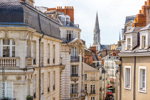 Street view on the beautiful residential buildings andchurch tower in Nantes city during the sunny day in France photo
