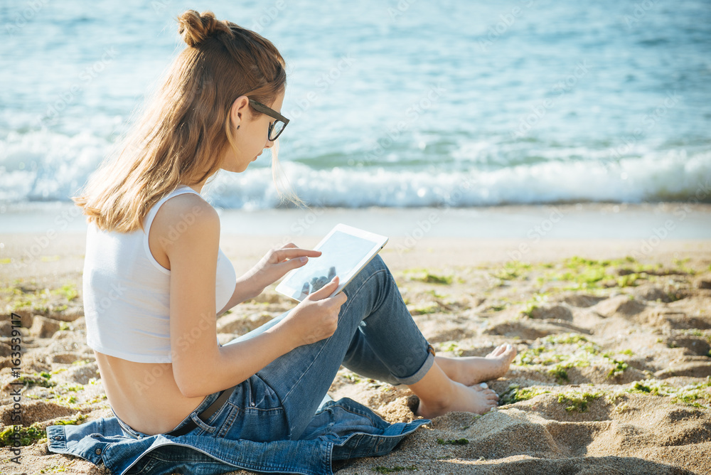Girl using a digital tablet by the sea.