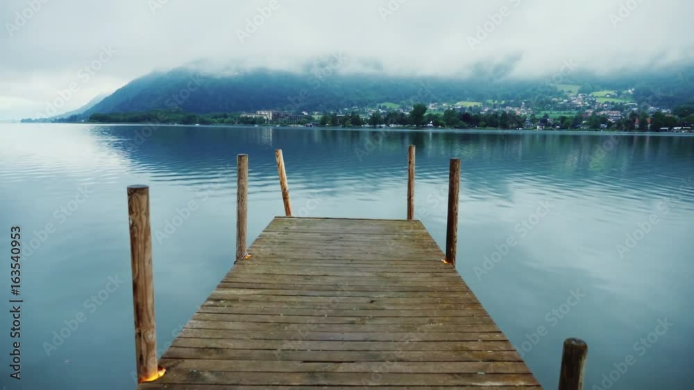 Wooden pier on a picturesque mountain lake in the Alps in Austria. Steaducam shot