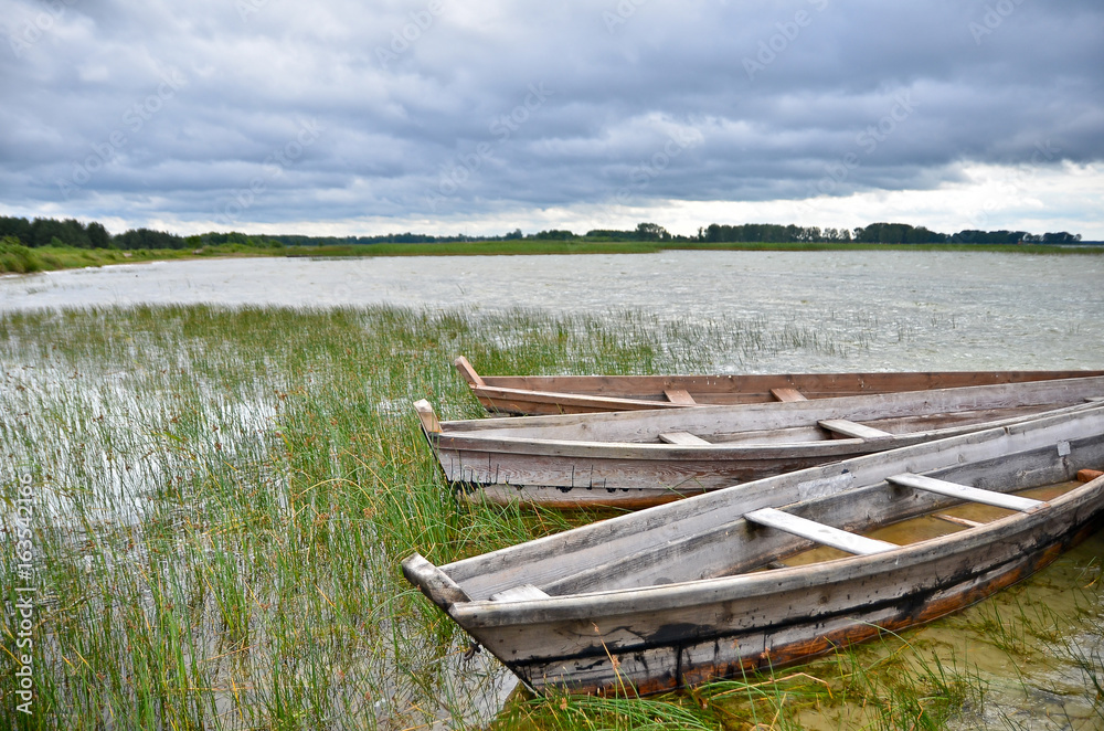 Old rustic wooden fishing boats on the lake at stormy weather, close up Old rustic wooden fishing boats on the lake at stormy weather, close up