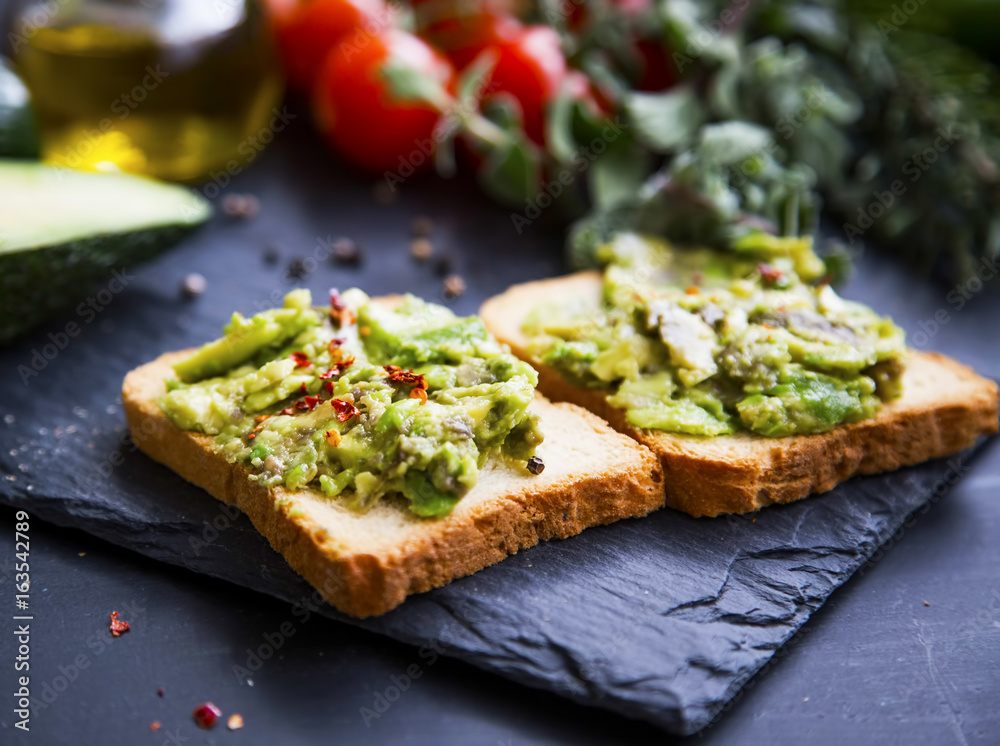 Smashed avocado on toast, tasty healthy appetizers with cherry tomatoes and herbs, olive oil