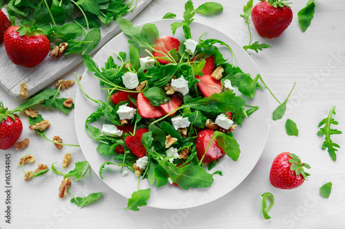 Fresh strawberry salad with feta cheese, arugula on white plate