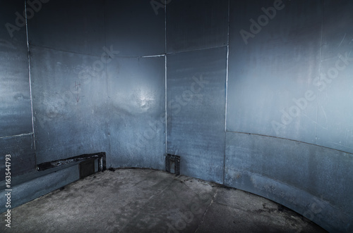 A scary cold  futuristic metal sheet prison cell  with a harsh concrete floor. An empty blue metal prison cell perfect for compositing.