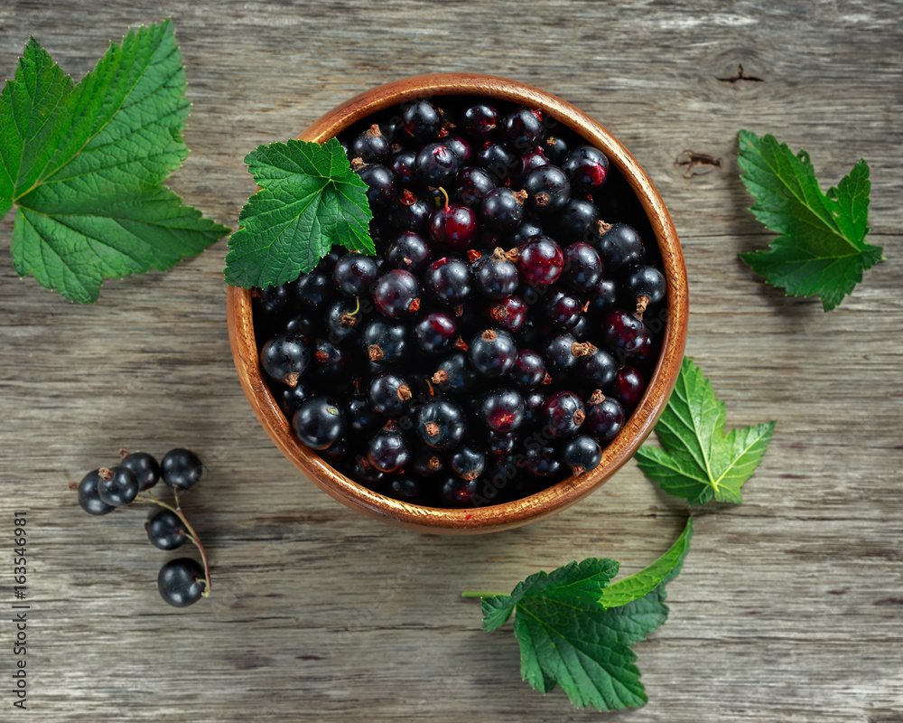 Fresh Juicy black currants in a wooden bowl on rustic table Fresh Juicy black currants in a wooden bowl on rustic table