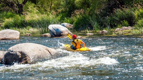 Kayaking along the rough river rapids. Training athlete.