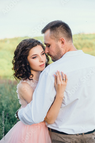 Beautiful wedding in nature. A handsome man with a scar on his face.  A loving couple is walking at sunset.