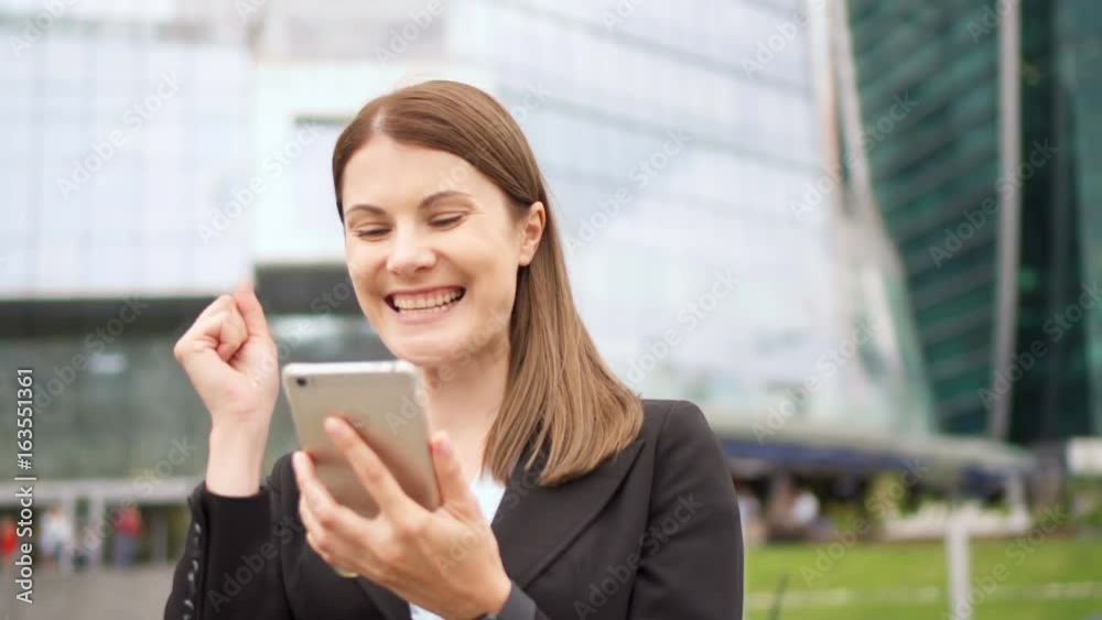 Businesswoman using smart phone in city downtown, professional female recieving good news excited Businesswoman using smart phone in city downtown, professional female recieving good news excited