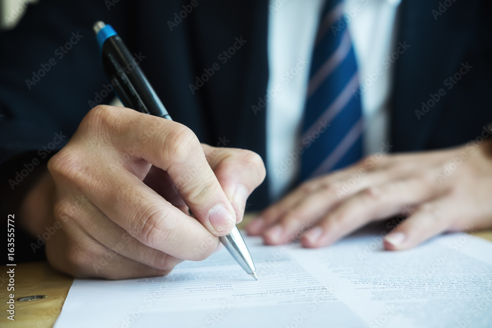 Business man signing business contract agreement, businessman handwriting signature on Formal Paper contract document at office desk Business man signing business contract agreement, businessman handwriting signature on Formal Paper contract document at office desk
