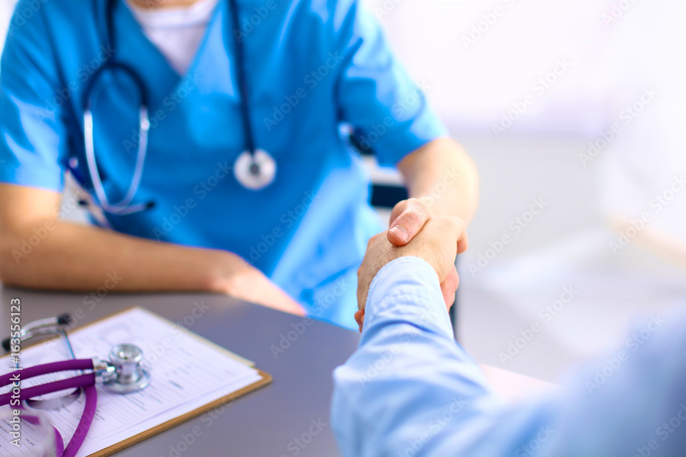 Attractive female doctor shaking a patient's hands in her office Attractive female doctor shaking a patient's hands in her office