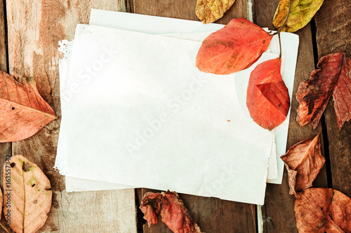 Beautiful maple leaves on vintage wooden background with old paper border des...