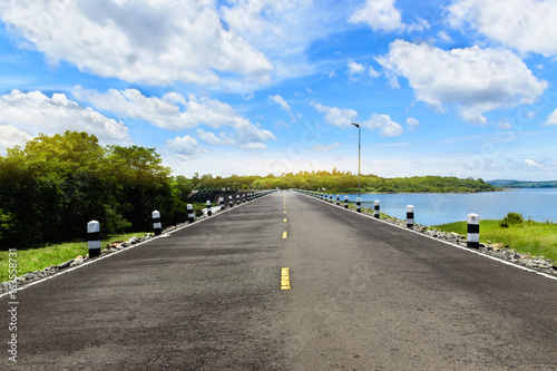 Smooth asphalt road along the dam.Top view landscape from dam under clouds an dblue sky located in Thailand.